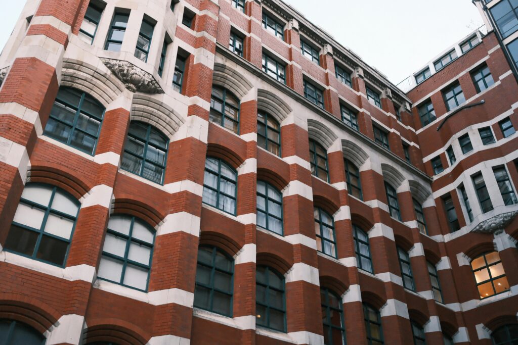Detailed view of a red brick building with arched windows in an urban setting.