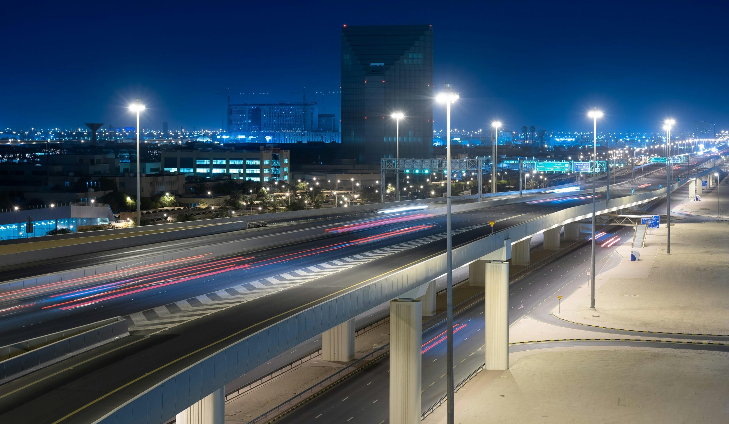 A vibrant urban landscape featuring a lit highway and towering buildings at night.