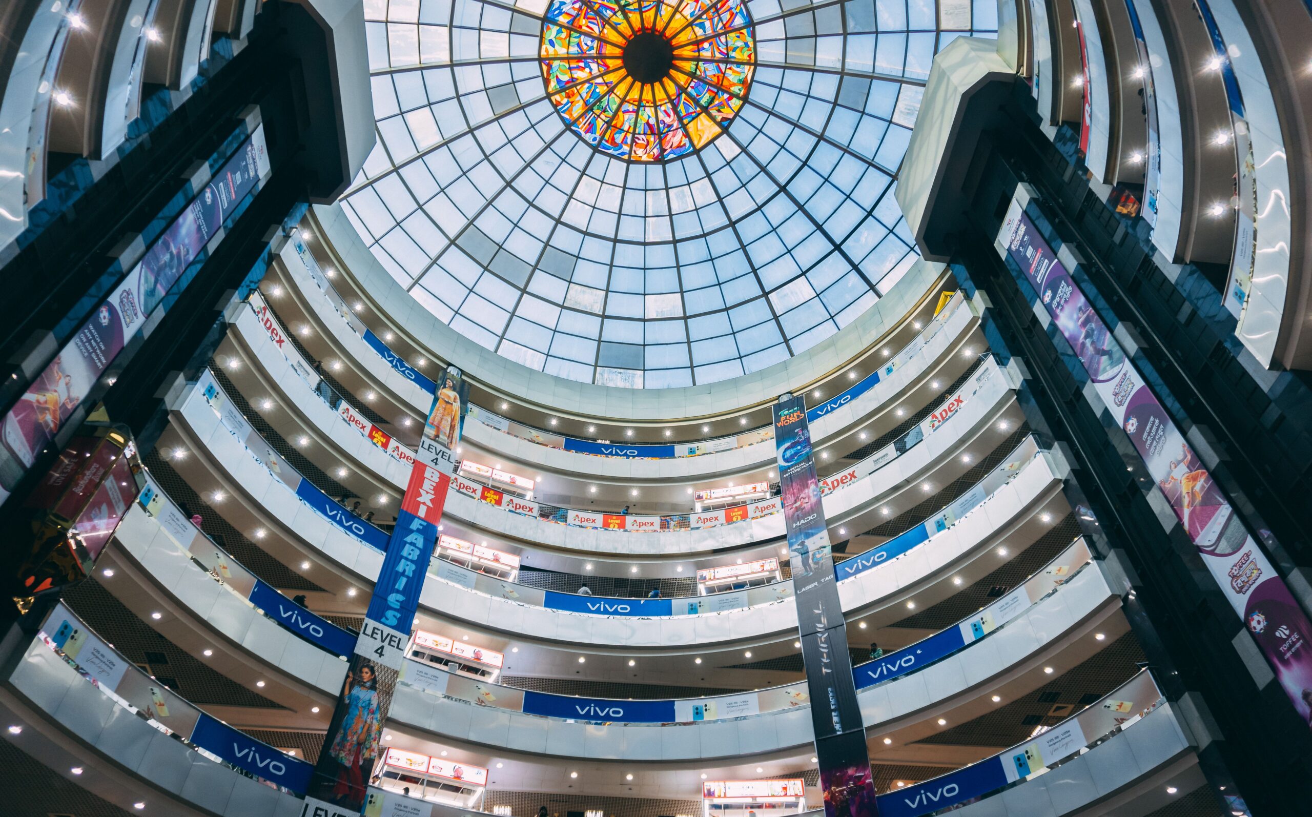 Interior view of a multi-level shopping mall with a stunning stained glass dome in Pattensen, Germany.