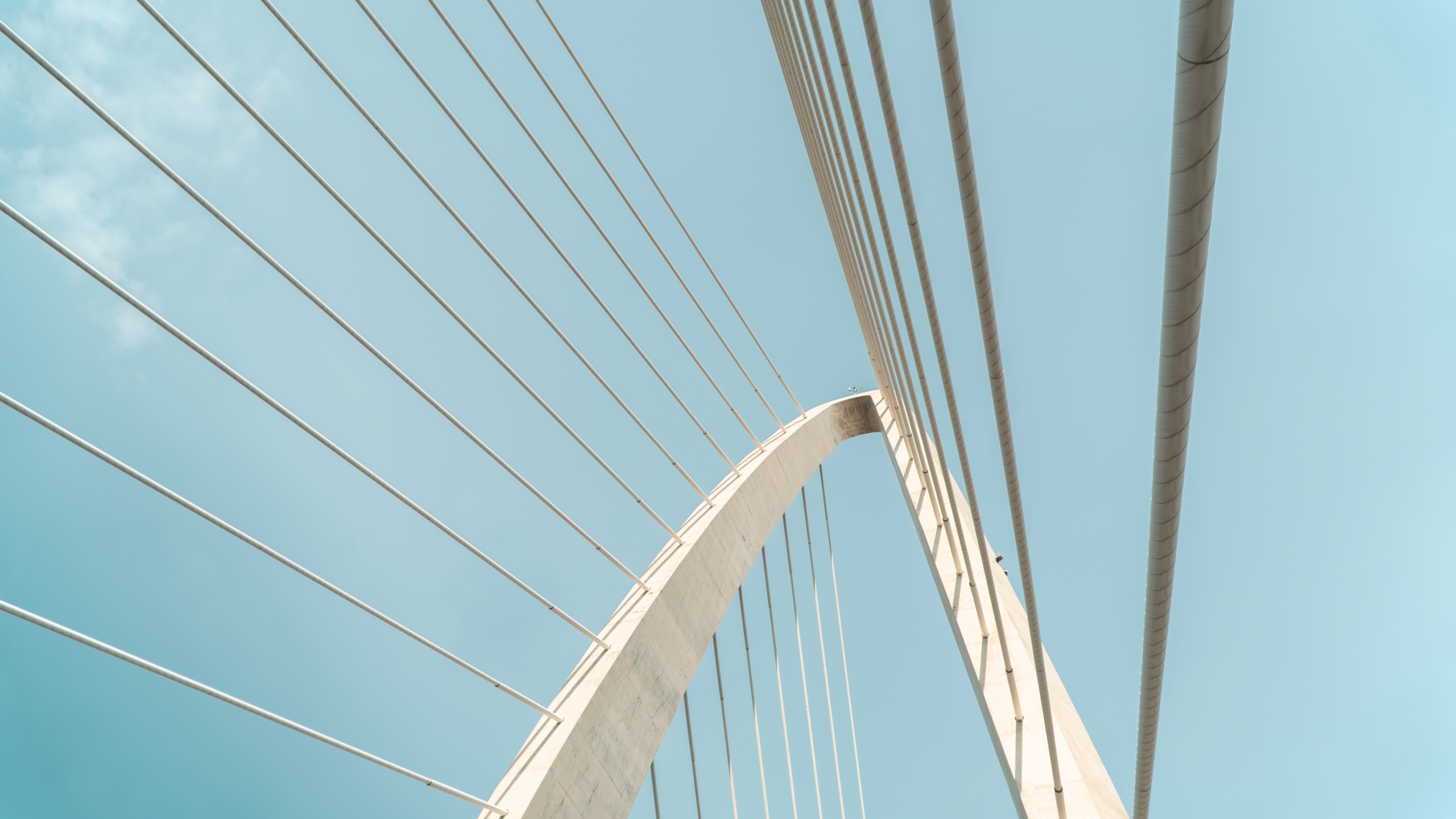 Elegant arch and cables of a modern suspension bridge with a clear blue sky.